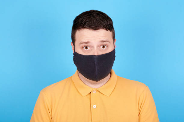 istock Angry brunette man in protection mask screaming, rage and mad expression. Isolated on blue background. 1256533739
