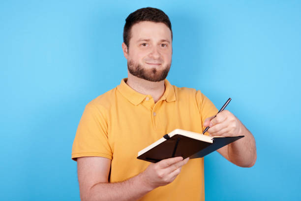 istock Brunette man use pen and notebook, idea concept. Isolated on blue background. 1256533830