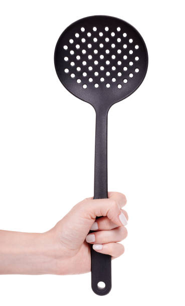 istock Hand with black plastic ladle, kitchen utensil. Isolated on white background. 1256536113