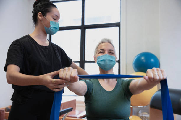 menschen, die bewegung im reha-zentrum tragen maske - physical therapy exercise machine exercising exercise equipment stock-fotos und bilder