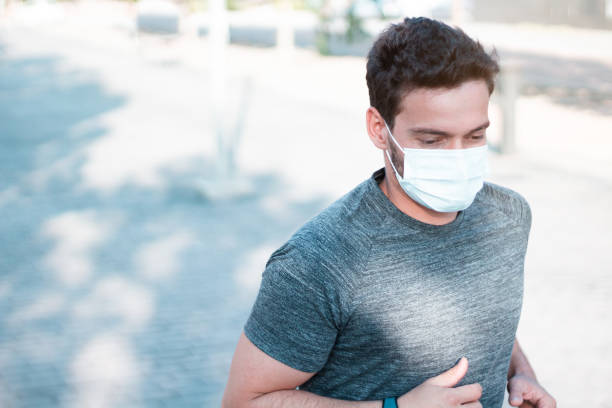 Close up of handsome man in medical mask running outdoors. Coronavirus pandemic situation. stock photo