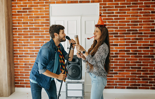 Young couple singing at a karaoke party at home