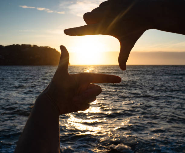 istock Hands catch sun at sunset time. Female fingers 1256547749