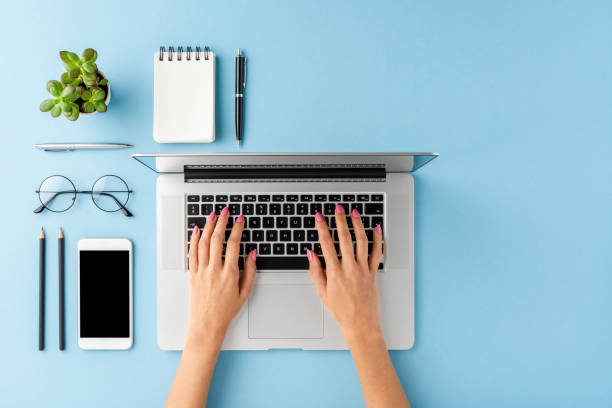 istock Woman’s hands using laptop on blue table with accessories. Business background with copyspace. Top view 1256548571