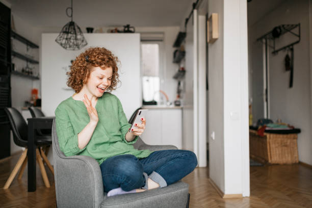 istock Beautiful cute smiling woman is using smart phone at home 1256551105