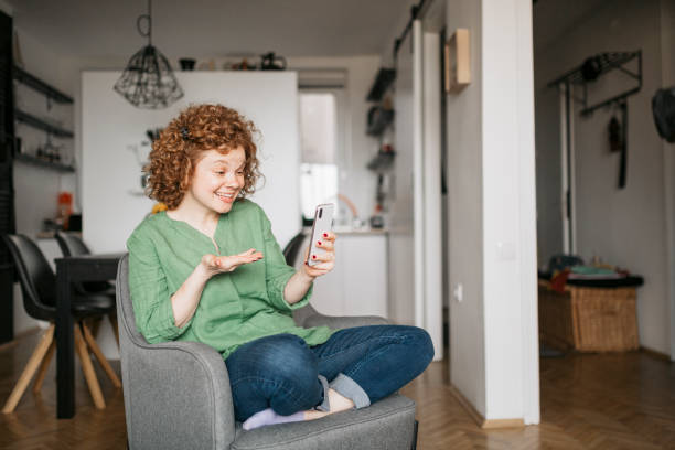 istock Beautiful cute smiling woman is using smart phone at home 1256551175
