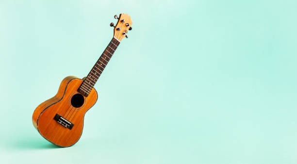 Brown ukulele isolated on abstract pastel turquoise background with wide copy space