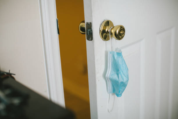 istock Protective face mask hanging on door knob 1256552636