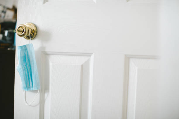 istock Protective face mask hanging on door knob 1256552800