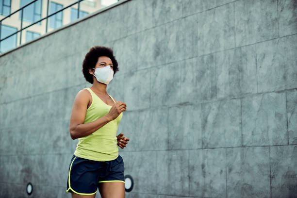 istock African American athletic woman jogging while wearing protective face mask. 1256556878