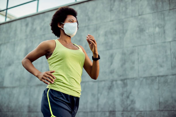 istock Below view of black female runner with protective face mask. 1256556945