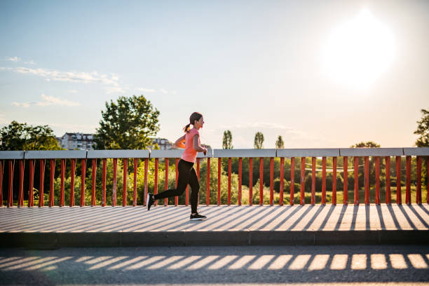istock Woman jogging across the bridge 1256557522