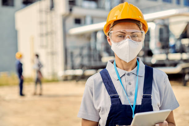 istock Female building contractor with digital tablet wearing face mask at construction site. 1256558468