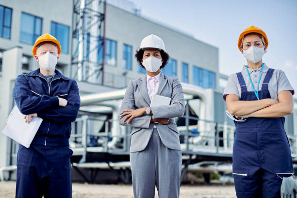 istock Team of confident civil engineers with protective face masks and construction site. 1256558588