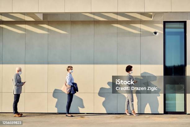 Full Length Of Business People With Protective Face Masks Waiting In A Line Outdoors Stock Photo - Download Image Now