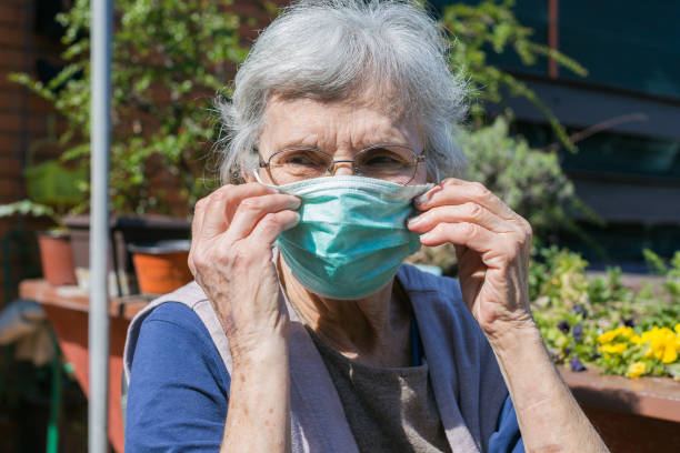 istock old woman putting on a face mask 1256560188
