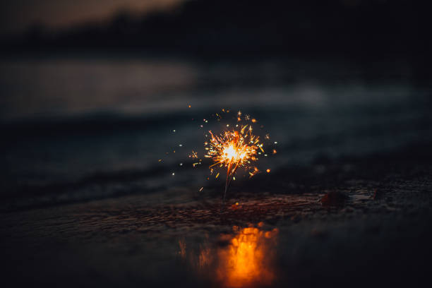 istock Burning Sparklers at Sunset on the Beach 1256562075