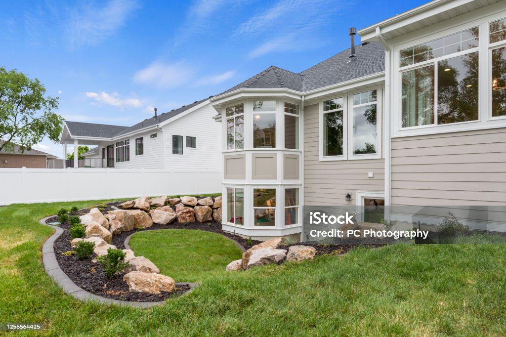 Rear exterior and back yard of new home multi-level yard lined with boulders and beautiful landscaping Siding - Building Feature Stock Photo
