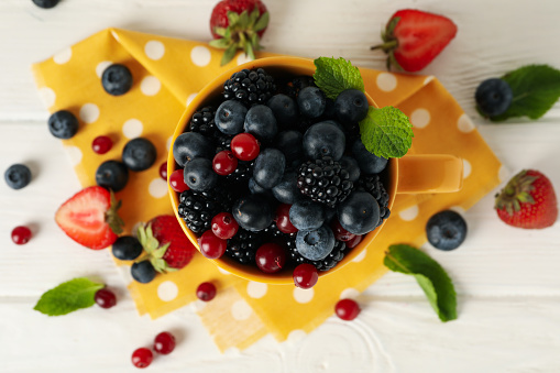 Composition with cup of fresh berries on wooden background, top view