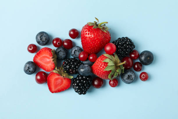 istock Mix of fresh berries on blue background, top view 1256565955