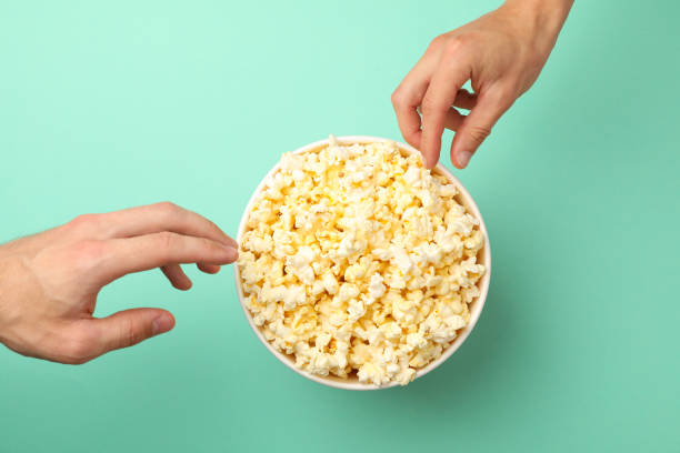 istock Men's hands take popcorn from a bucket on mint background 1256567014