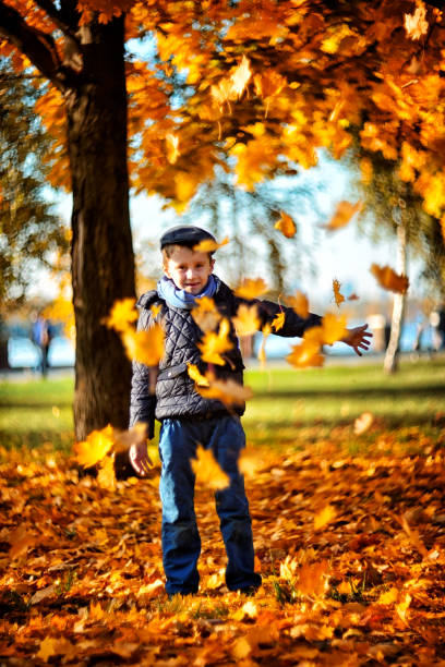 istock Boy playing with leaves in autumn park 1256567081