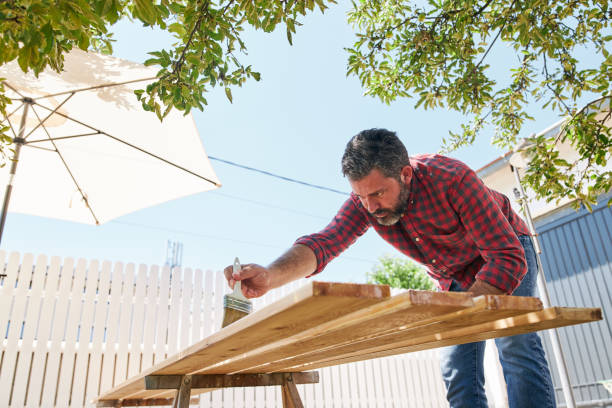 istock Construction carpenter using varnish on wooden planks outdoors 1256567543