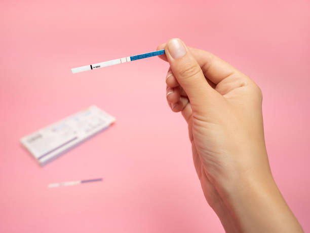 Female hand holding positive pregnancy test isolated on pink background. The abbreviation HCG on the blue bar means Human chorionic gonadotropin is a hormone produced by cells that are surrounding a growing embryo syncitiotrophoblast initially , which eventually forms the placenta after implantation. mano femenina sosteniendo prueba de embarazo positiva aislada sobre fondo rosa. la abreviatura hcg en la barra azul significa gonadotropina coriónica humana es una hormona producida por las células que rodean un creciente sincromiotrotrofoblasto embriona