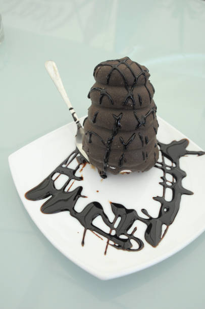 Chocolate cake for dessert after lunch. Creamy chcolate cake with chocolate topping served on plate with fork.