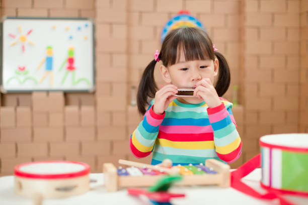 istock toddler girl play harmonica at home for home schooling 1256569236