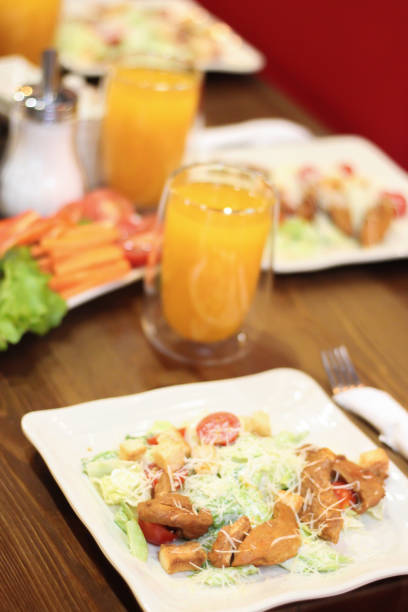 istock Caesar salad in the restaurant and orange juice. Caesar salad with chicken 1256570534