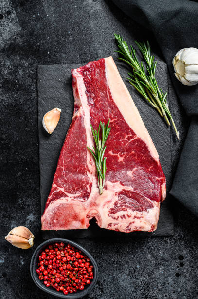 istock T bone steak. Organic raw Tbon beef. Black background. Top view 1256572522