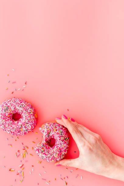 istock Hand holding donut with icing and sprinkles. Flat lay, top view 1256572569