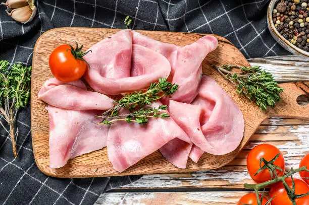 Sliced ham. Fresh prosciutto. Pork ham sliced. White wooden background. Top view.