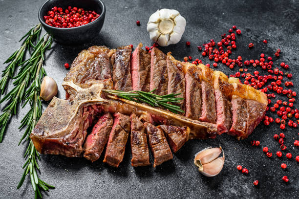 istock Sliced Grilled T-bone steak. Cooked tbone beef meat. Black background. Top view 1256573623
