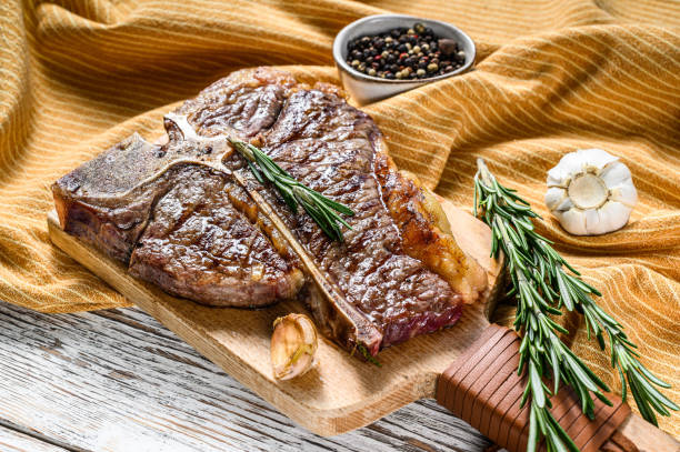 istock Grilled T bone steak on a chopping Board. Cooked tbone beef. White wooden background. Top view 1256573686