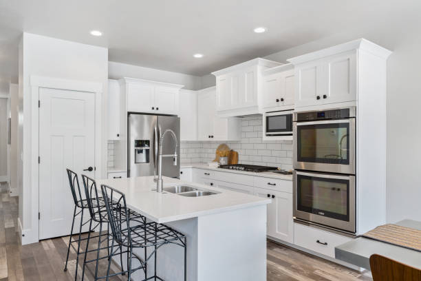 White kitchen with smaller island and stainless steel appliances Stainless steel double oven and french door refrigerator add contrast to white kitchen kitchen stock pictures, royalty-free photos & images