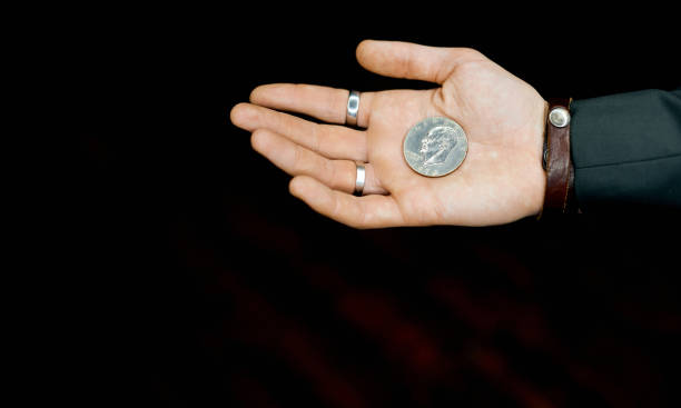 istock one coin in a man's palm on a black background local light 1256575952