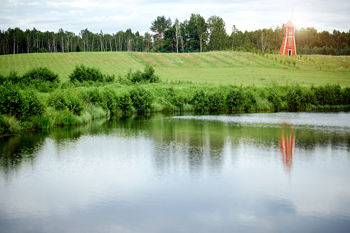 colorful landscape. red mill near the pond in the field with a reflection of . High quality photo