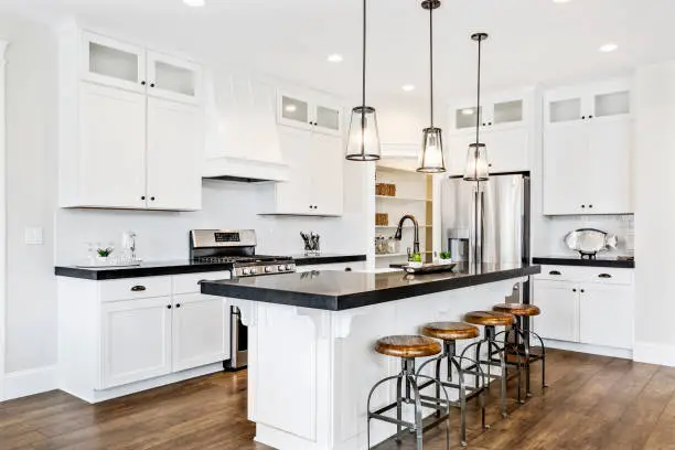 Photo of White gourmet kitchen with black countertops