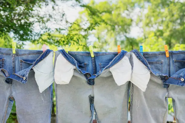 Photo of The washed jeans hang on a clothesline. Pockets turned inside out. Drying clothes on the street. Life style.