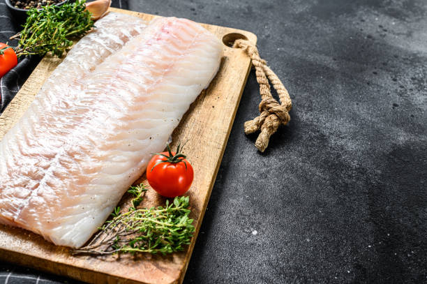 istock Fresh Raw Cod loin fillet with thyme.  Black background. Top view. Copy space 1256577622