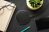 Wireless charging on a black slate with a book, pencil, smartphone, glasses and a plant.