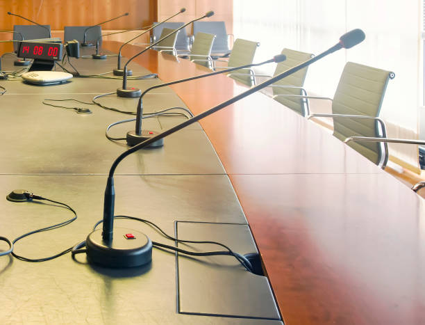 istock Microphone on a wooden table and empty chairs in a boardroom. 1256577711