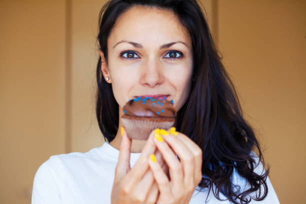 istock Young woman eating a cupcake 1256578974