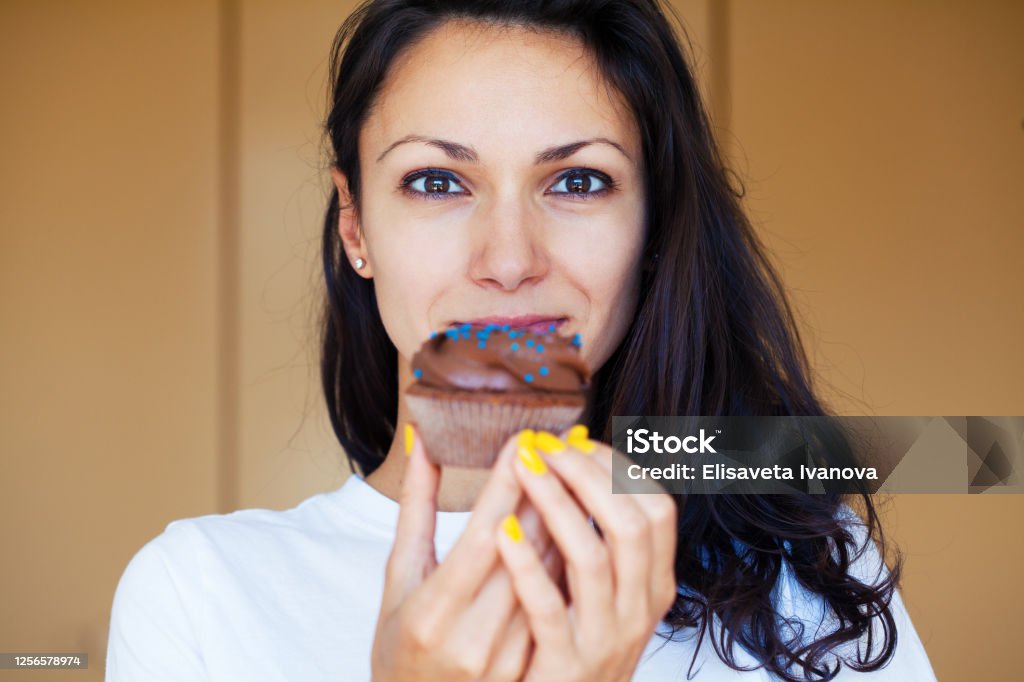 Young woman eating a cupcake Eating Stock Photo