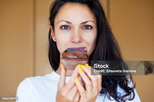 Young Woman Eating A Cupcake Stock Photo - Download Image Now - Eating, Cupcake, Dessert - Sweet Food