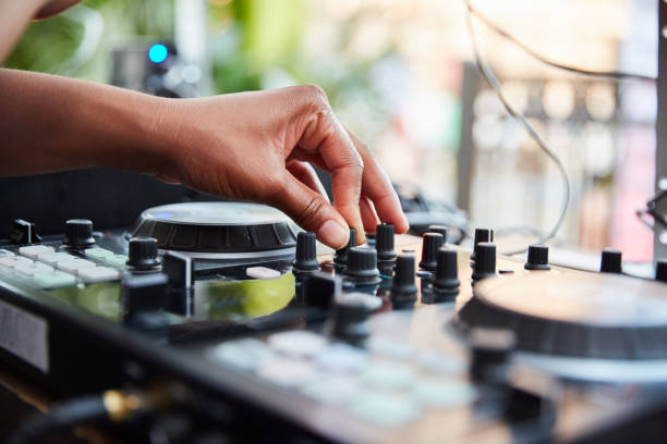 DJ adjusts the volume on the turntable at a party. An African American DJ adjusts the volume on the turntable at an outdoor summer party. dj stock pictures, royalty-free photos & images