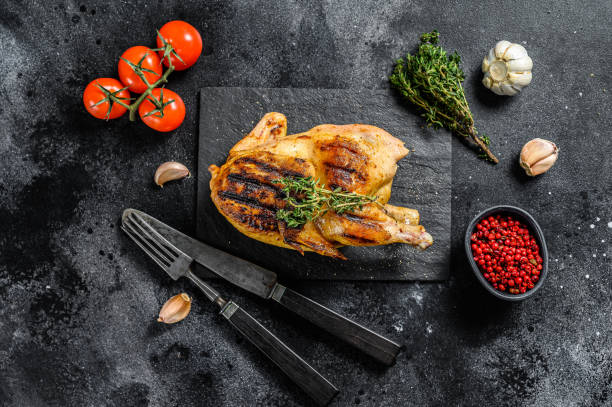 istock Grilled whole organic chicken with thyme. Black background. Top view 1256581360