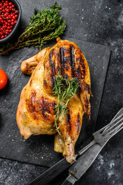istock Grilled whole organic chicken with thyme. Black background. Top view 1256581460